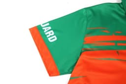 A quarter-zip uniform in vibrant green and orange, featuring a logo on the sleeve.