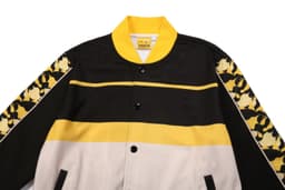 A multi-coloured jacket featuring black, white, and yellow stripes, with patterned sleeves and a logo.