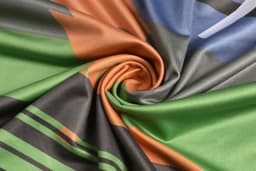 A long sleeve T-shirt featuring a swirling pattern in green, orange, and grey with a logo.