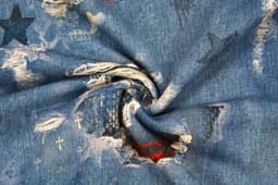 A close-up view of denim fabric featuring various coloured patches, stars, and distressed details.