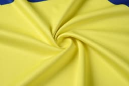 A yellow fabric with a smooth texture, featuring a blue outline. The fabric is arranged in a spiral pattern.