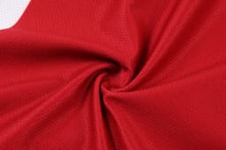 A close-up of red fabric with a textured pattern, showcasing the material of women’s soccer uniform shorts.