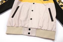 A multi-coloured jacket featuring black, yellow, and beige elements with a branded logo.