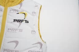 A white and yellow puffer vest with a removable hood and branding, featuring a sleeveless design.