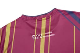 A maroon t-shirt featuring vertical stripes in yellow and blue, made from micro mesh fabric with a logo.