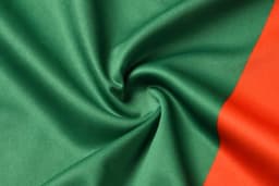 A vibrant fabric featuring green and orange sections, showcasing a smooth texture and folded design.