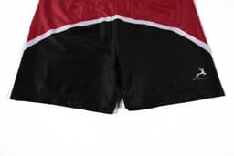 Red and black promotional shorts with a curved design and a small logo on the side.