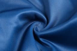 A blue fabric material displayed in a swirl pattern, showcasing a smooth texture. It features a branded logo.