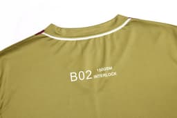 A khaki shirt featuring a white collar and a logo on the back, with red accents near the shoulders.