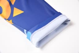 A sleeve of a blue garment featuring a vibrant sun design, with a contrasting light blue cuff.