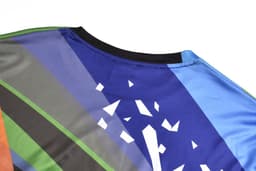 A long sleeve t-shirt featuring a multi-coloured design with shades of blue, green, orange, and grey, and a logo.