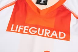 A white and orange sports uniform with "LIFEGUARD" displayed prominently on the front and a logo on the collar.
