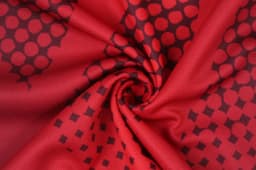 A red fabric with a textured pattern of circles and squares, featuring a smooth, swirling design.