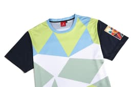 A colourful t-shirt featuring geometric patterns in light blue, green, and navy with a logo on the sleeve.