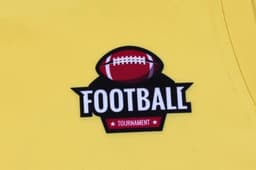 A bright yellow sports singlet featuring a football logo and a branding patch.