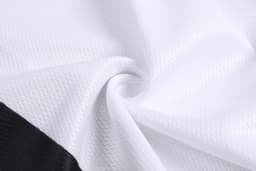 A close-up of textured fabric featuring white material with black accents, suitable for baseball training pants.