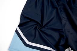 Navy blue woven school shorts with a light blue and white stripe detail. The shorts have a logo on them.