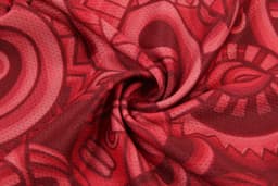 A red women's basketball uniform singlet featuring a vibrant, abstract pattern and a logo.