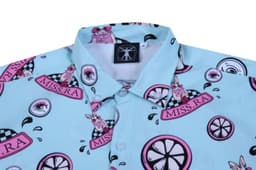 A light blue shirt featuring a playful pattern with cartoon rabbits, lemons, and various badges, including a logo.