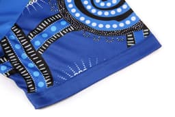 A blue sublimated T-shirt featuring Aboriginal artwork with intricate patterns and a black logo.