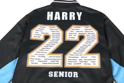 A black varsity jacket featuring blue sleeves and a large "22" with a list of names and a logo on the back.