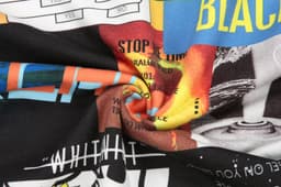 A patterned fabric featuring vibrant colours and various designs, showcasing graphics and text elements.