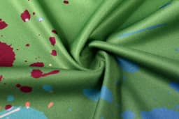 A green fabric featuring a splash design with red and blue accents, suitable for a running singlet.