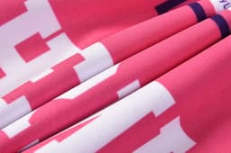 A vibrant pink hoodie with a quarter zipper, featuring a textured fabric and a logo.