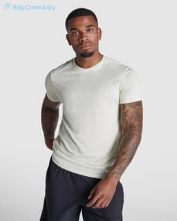 A light green t-shirt with short sleeves, featuring a logo, modelled by a person with tattoos.