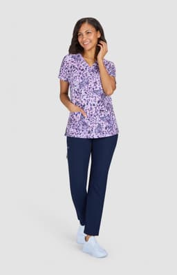 A printed purple top with short sleeves, paired with navy pants, and worn with light blue shoes.