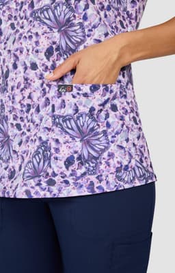 A floral print top in shades of purple featuring butterfly designs and a side pocket, with branding visible.