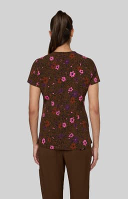 A floral print top in brown, featuring pink and purple flowers, viewed from the back on a model.