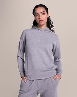 A grey hoodie with a relaxed fit and a hood, worn by a model against a neutral background.