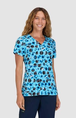 A woman wearing a blue v-neck top with a colourful print featuring various patterns. The top has a logo.