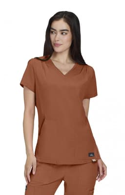 A woman models a brown Sari Top, featuring a V-neck and short sleeves, with pockets and a logo.