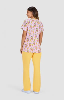 A woman wearing a pink top with a colourful print and yellow pants, seen from the back. The outfit features a logo.