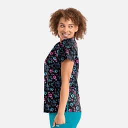 A women's V-neck top featuring a floral print in pink, purple, and blue on a black background. It has a logo on the side.