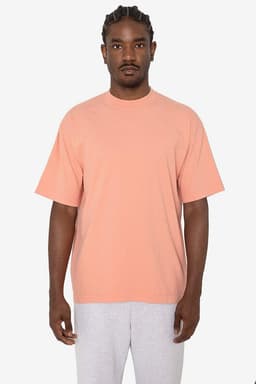 A short sleeve crewneck tee in a soft peach colour, featuring a relaxed fit and a branding logo.