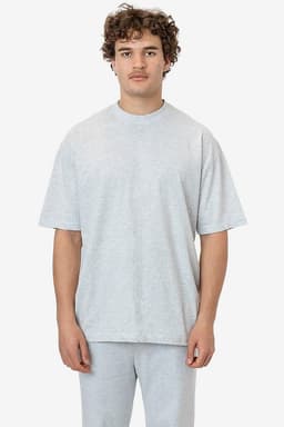 A model wearing a light grey short sleeve crewneck tee, featuring a relaxed fit and a logo on the sleeve.