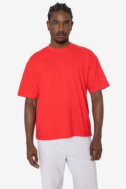 A red short sleeve garment-dyed crewneck tee displayed on a model, paired with grey sweatpants. The tee features a brand logo.