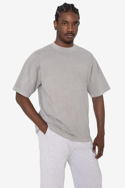 A grey short sleeve crewneck tee displayed on a model, featuring a relaxed fit and a logo.
