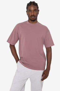 A short sleeve crewneck tee in a muted pink colour, featuring a relaxed fit and a logo.