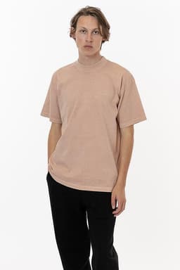 A crewneck tee in a soft peach colour, featuring short sleeves and a relaxed fit. It has a branding logo.