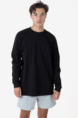 A long sleeve crewneck tee in black, paired with light grey shorts, worn by a model against a plain background.