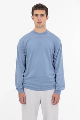 A light blue long sleeve crewneck tee featuring a logo on the front, styled with grey sweatpants.