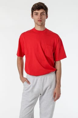 A red short sleeve T-shirt featuring a chest pocket, worn with grey sweatpants, with a logo visible on the shirt.