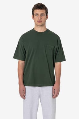 A green short sleeve t-shirt featuring a pocket, worn by a model with grey pants. It has a logo on it.