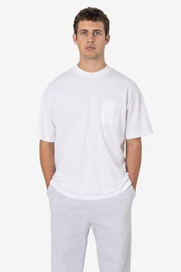 A white short sleeve T-shirt featuring a pocket, worn with grey trousers. The shirt has a subtle logo on it.