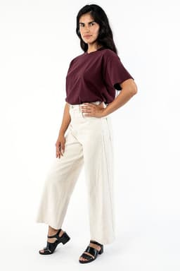 A woman poses wearing a burgundy wide tee and cream-coloured wide-leg trousers, paired with black sandals.