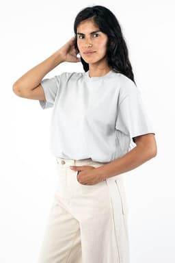 A wide tee in light grey, featuring a relaxed fit and short sleeves, worn with high-waisted trousers. It has a logo.